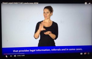 Woman in dark sheet or video screen signing with blue box and captions below her